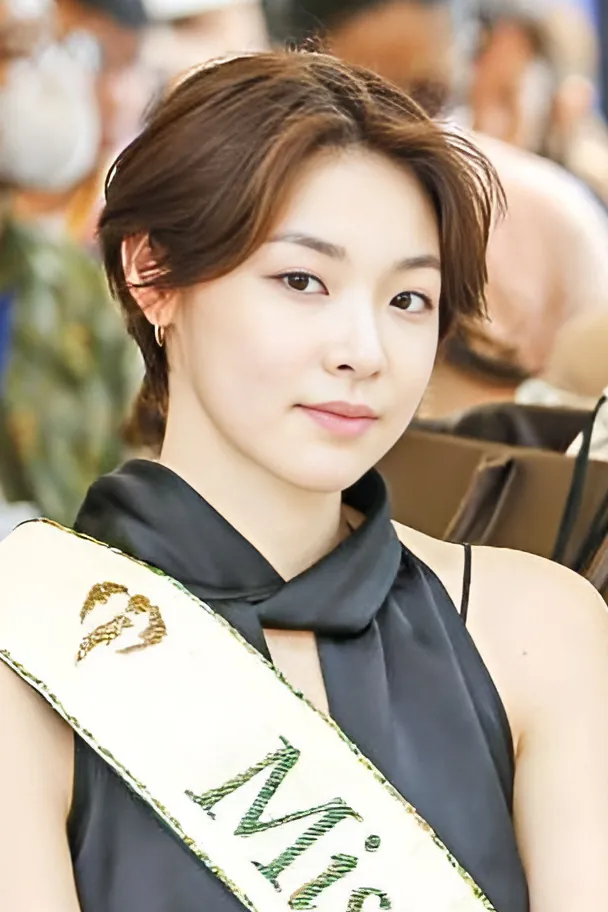 Mina Sue Choi with short brown hair wearing a Miss Earth sash